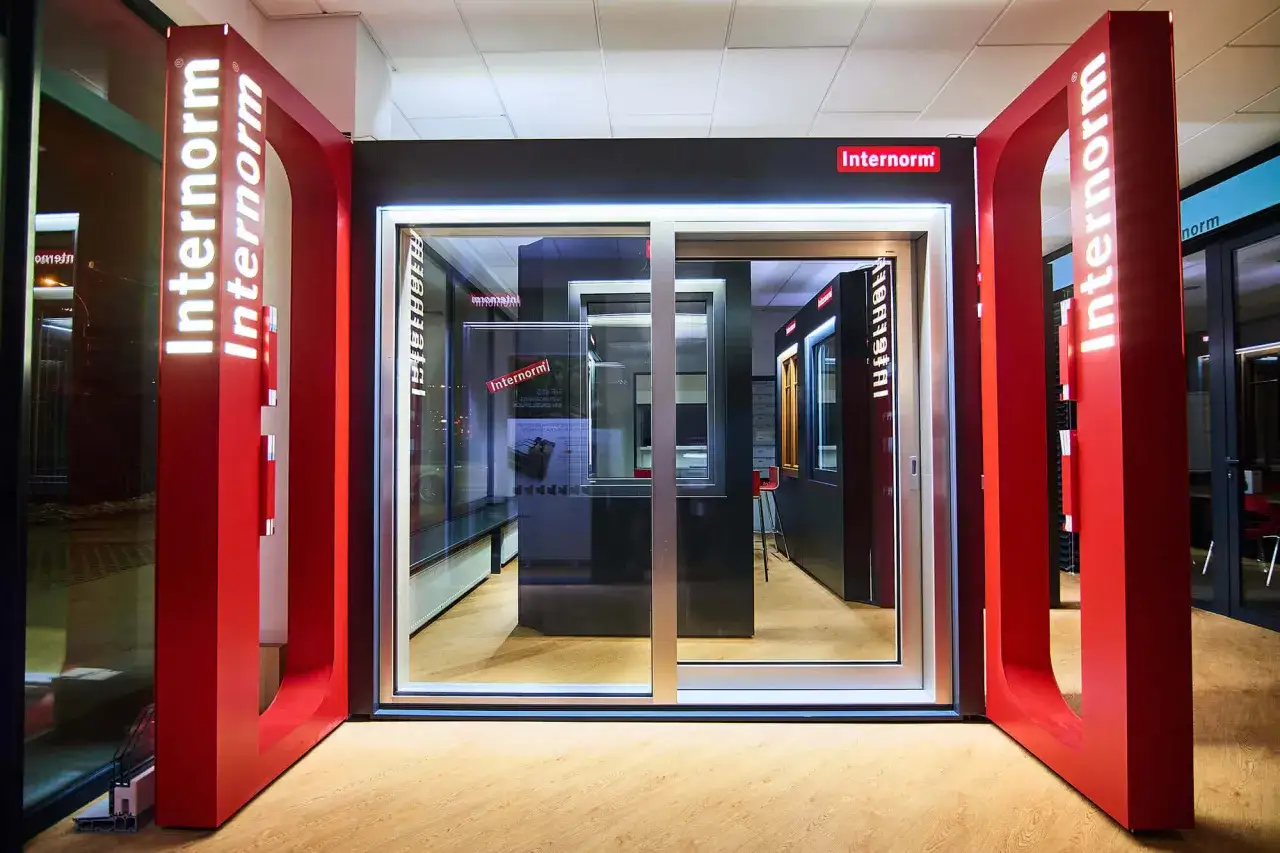 Nowoczesny salon z oknami i drzwiami Internorm, z czerwonymi elementami i ekspozycją.