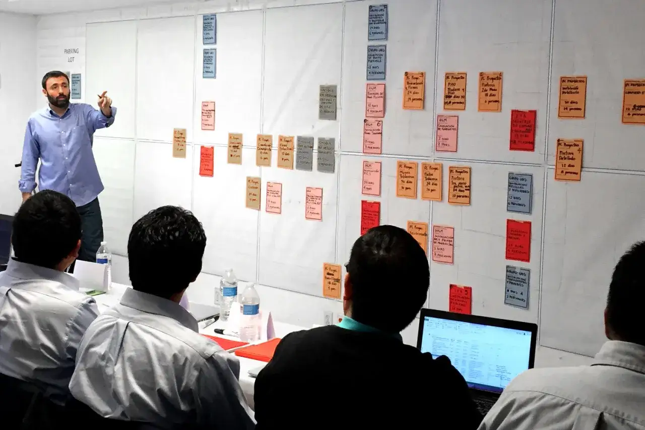 Un equipo colabora en un tablero visual, aplicando principios de **lean construction** para planificar tareas y optimizar procesos.