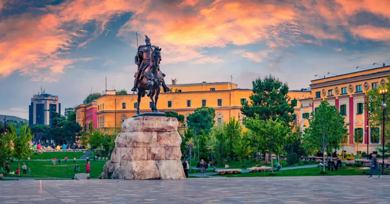Skanderbeg na koniu, plac w Tiranie. Warto zobaczyć to miejsce o zachodzie słońca, z kolorowym niebem i budynkami w tle.