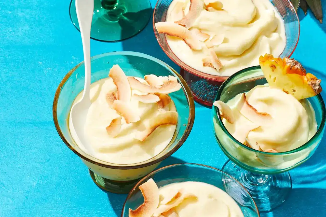 Cremiges Pina Colada Eis in Schalen, garniert mit Kokoschips und Ananas. Ein tropischer Genuss!