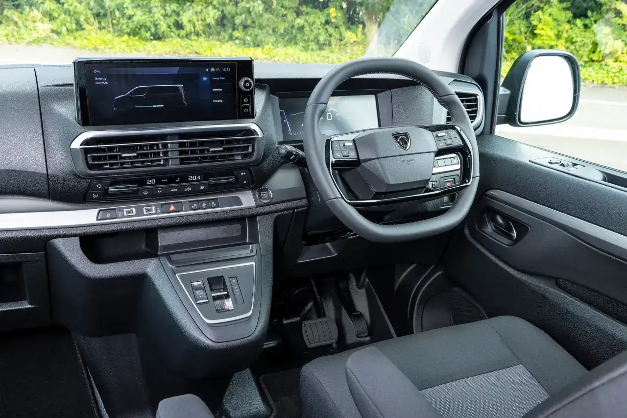 Wnętrze Peugeot Traveller z ekranem multimedialnym, kierownicą i panelem klimatyzacji.
