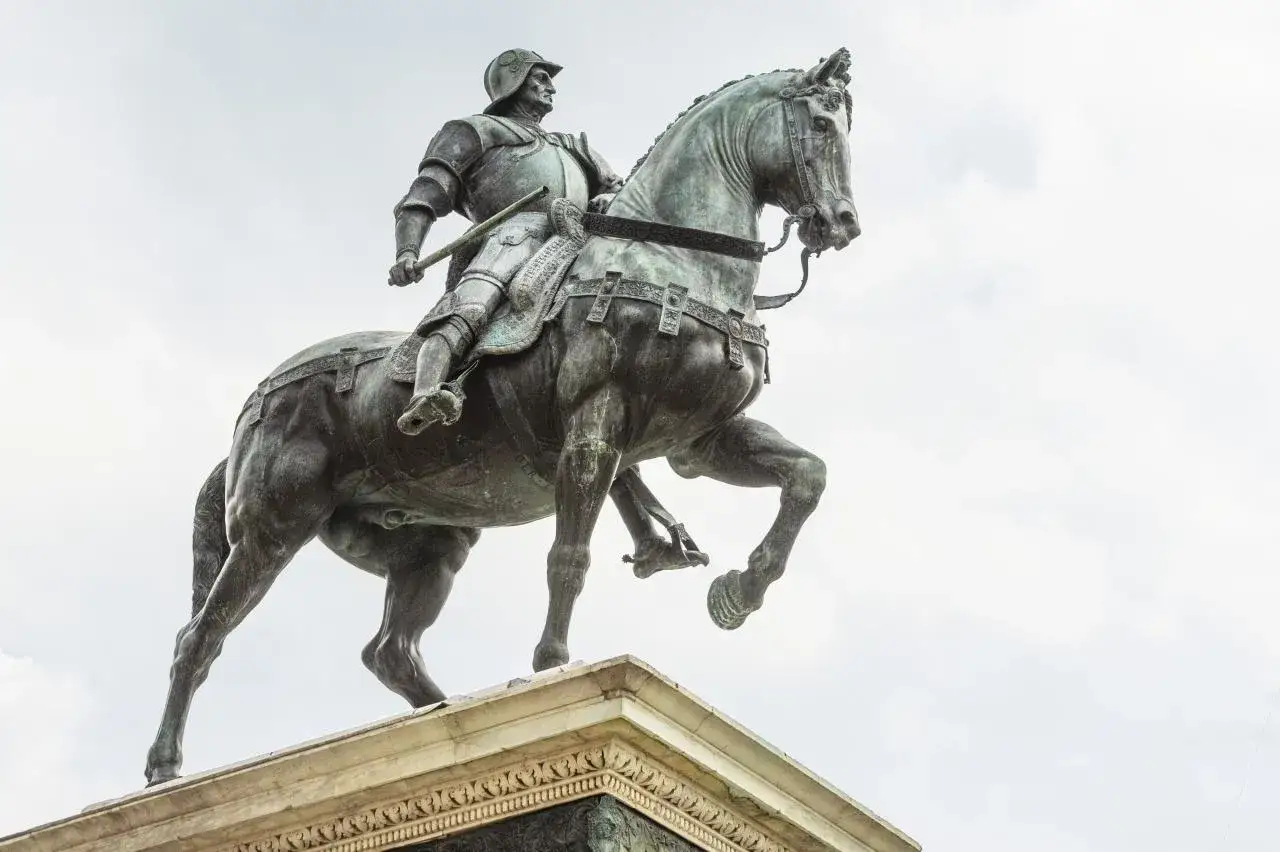 Statue &eacute;questre en bronze de Bartolomeo Colleoni, arm&eacute; et fier, sur son cheval cabr&eacute;, sous un ciel clair.