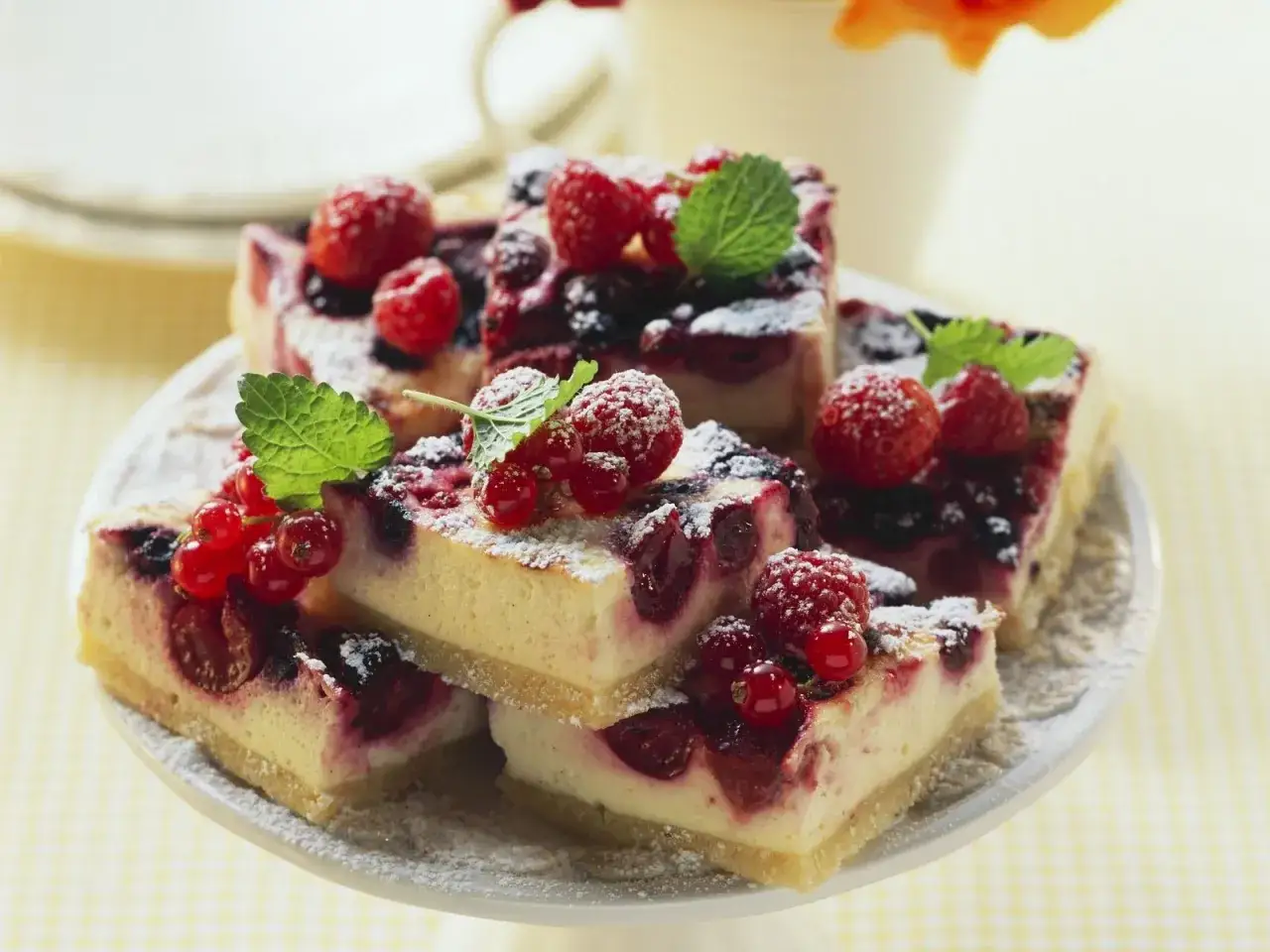 Saftige beerentorte ohne backen, belegt mit frischen Himbeeren, Johannisbeeren und Minze, bestäubt mit Puderzucker.