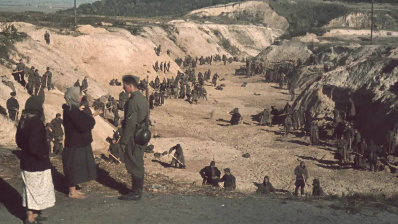 Arbeiter und Soldaten in einer Grube bei Kiew 1941. Frauen in dunkler Kleidung stehen im Vordergrund.
