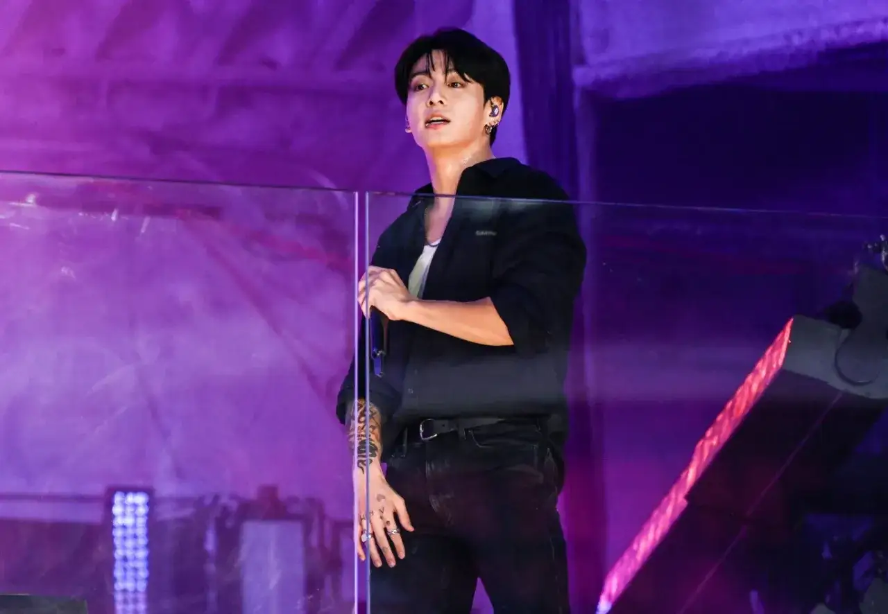 Jungkook z BTS na scenie, w czarnej koszuli i spodniach. Fani zastanawiają się, czy Jungkook z BTS ma dziewczynę.