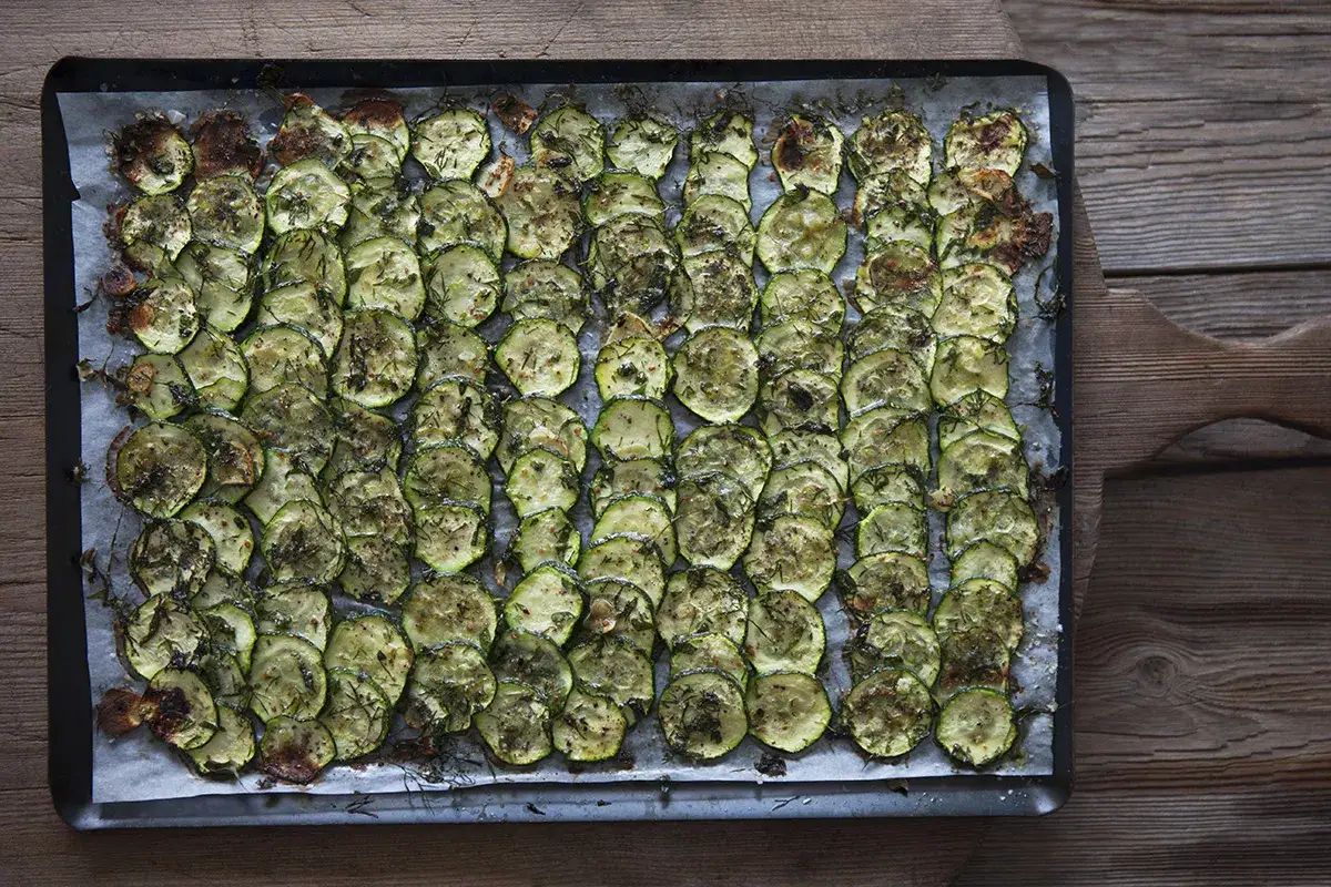 Ugnsbakade skivor av zucchini, kryddade med örter och lätt gyllene. Enkel och god rätt med zucchini i ugn.