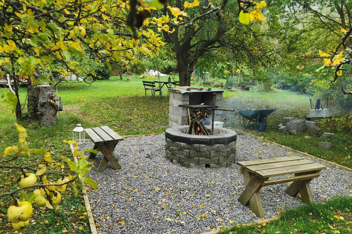 En mysig murad grillplats med bänkar och bord i en höstträdgård.