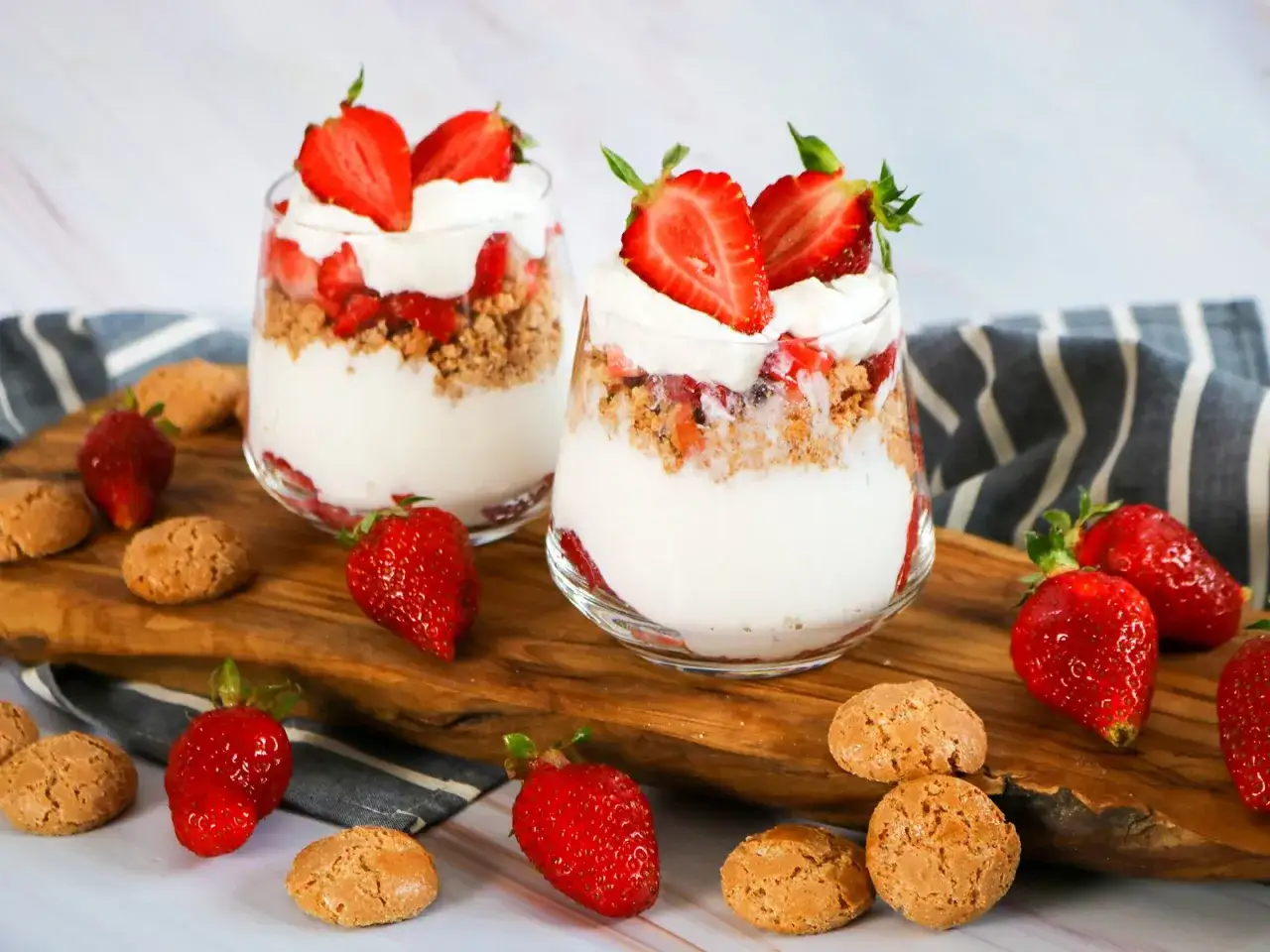Zwei Gläser mit Erdbeer-Dessert aus Quark und Joghurt, garniert mit frischen Erdbeeren und Keksen.