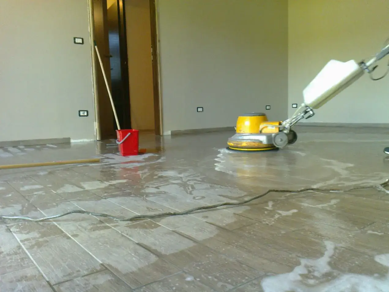 Macchina per la levigatura del travertino in azione, con acqua e schiuma sul pavimento.