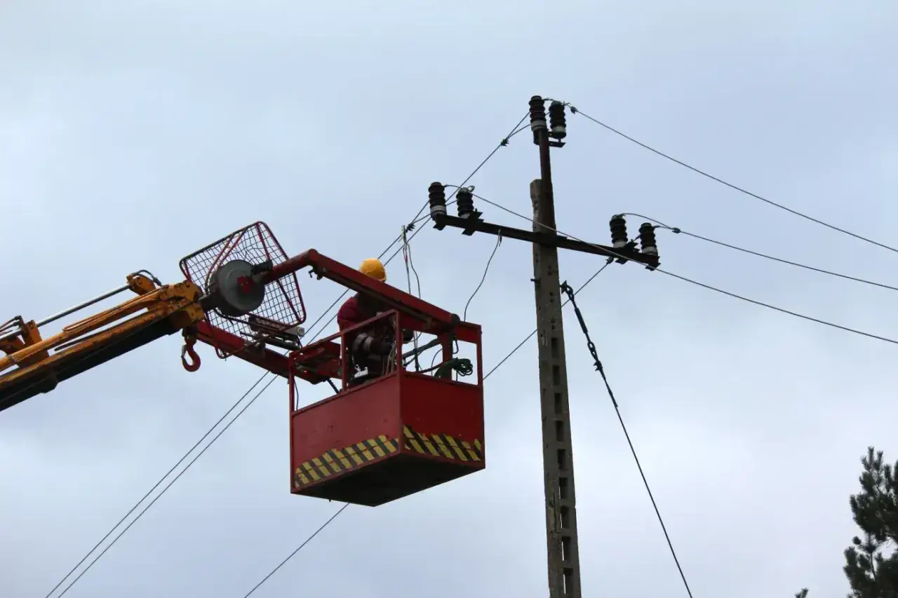 Pracownik w koszu podnośnika naprawia linię energetyczną. Oby tylko nie było awarii, bo wtedy czeka nas bonifikata za brak prądu.