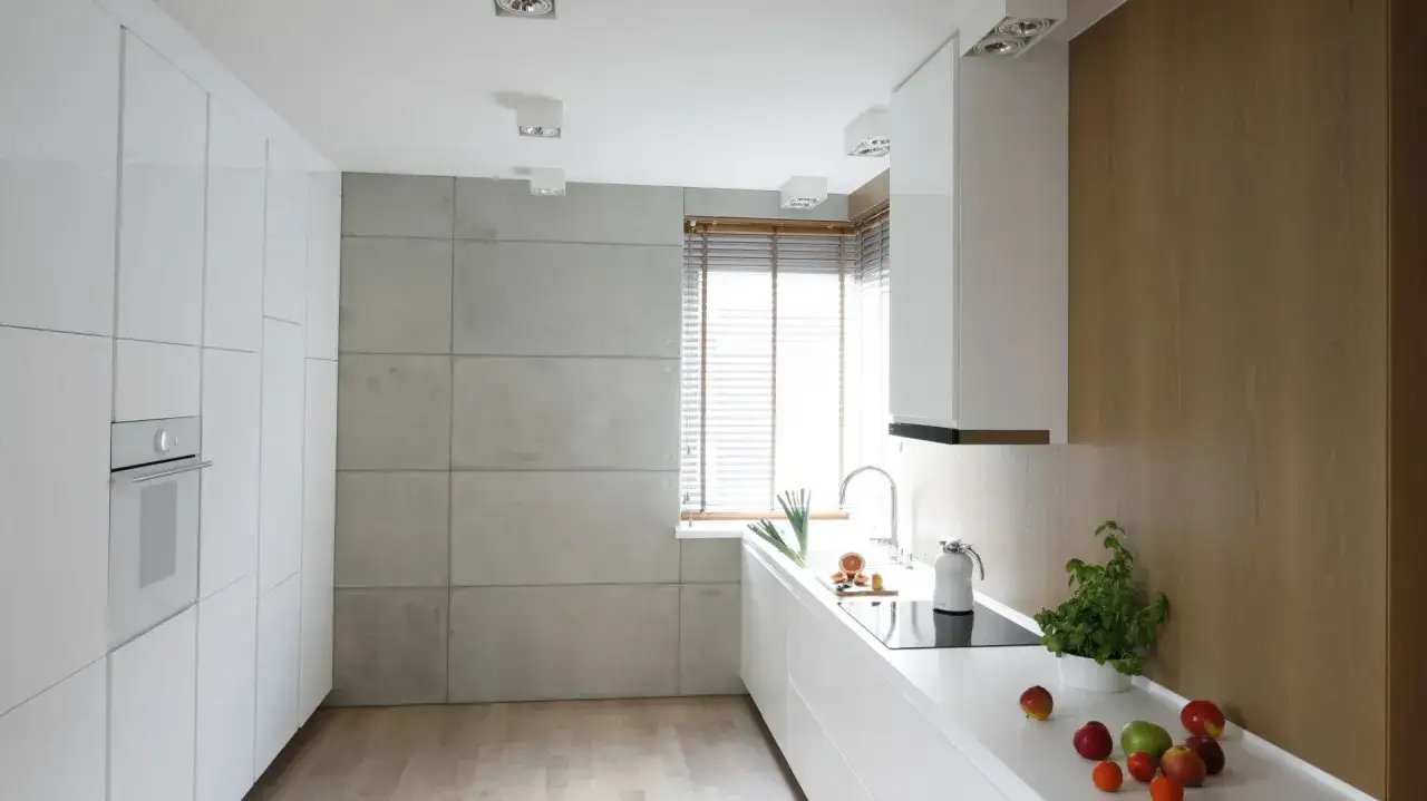 Nowoczesna kuchnia z białymi frontami i betonem architektonicznym na ścianie. Inspiracje dla miłośników surowego stylu.