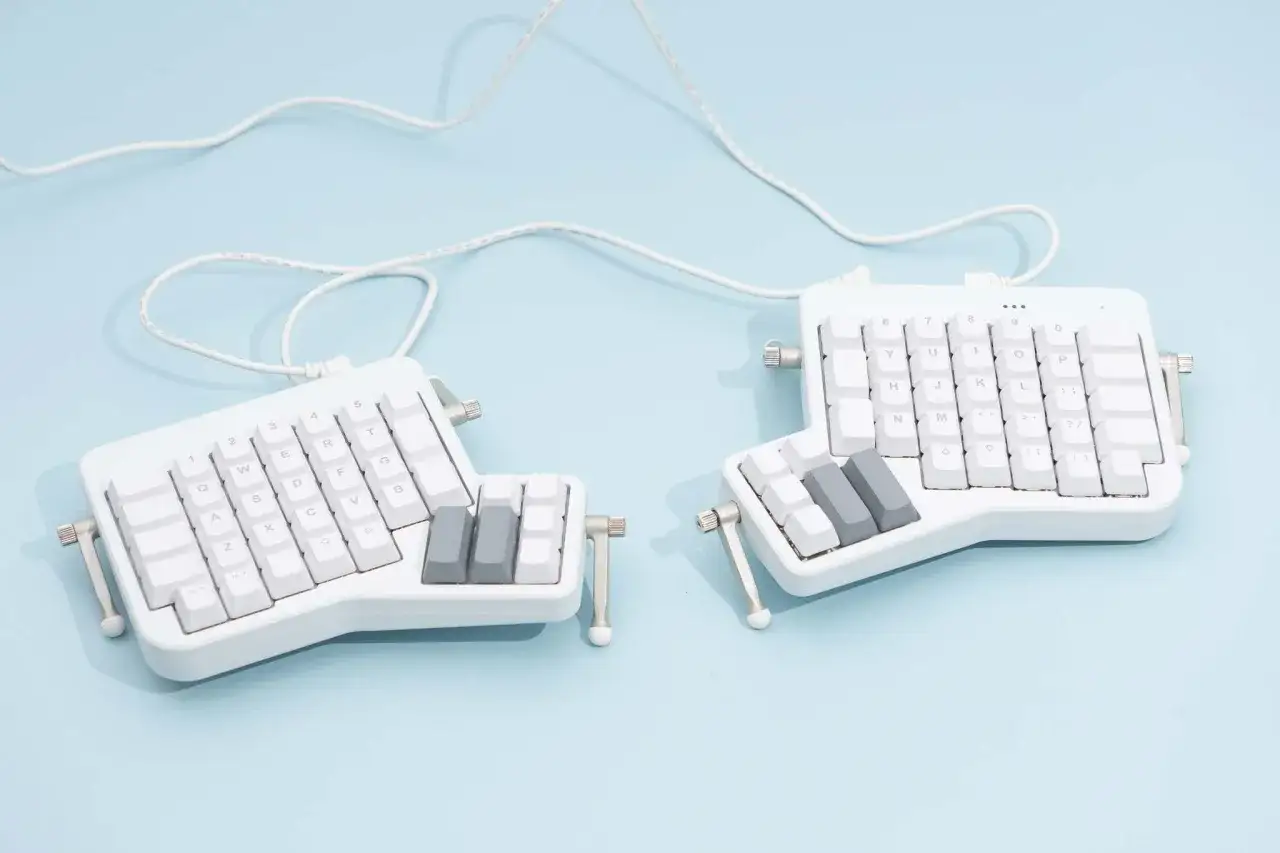 Ergonomiczna, biała klawiatura do 300 zł, podzielona na dwie części, z białymi i szarymi klawiszami.