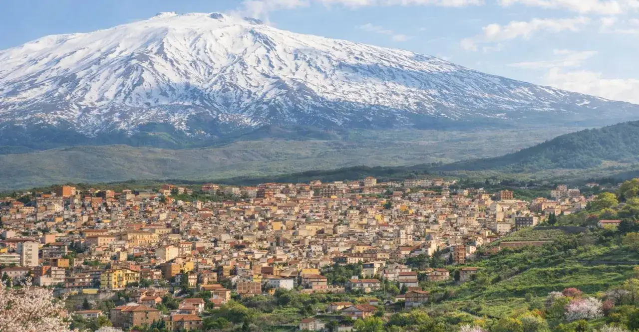 Vista di un paese siciliano con l'Etna innevato sullo sfondo. Un paesaggio incantevole di Catania e dintorni.
