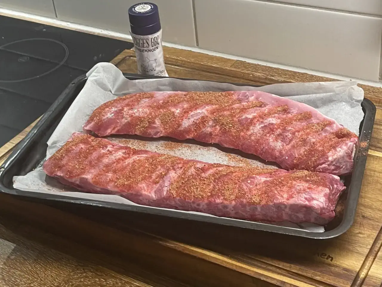 Två ugnsbakade kamben, kryddade och redo för ugnen. En burk med