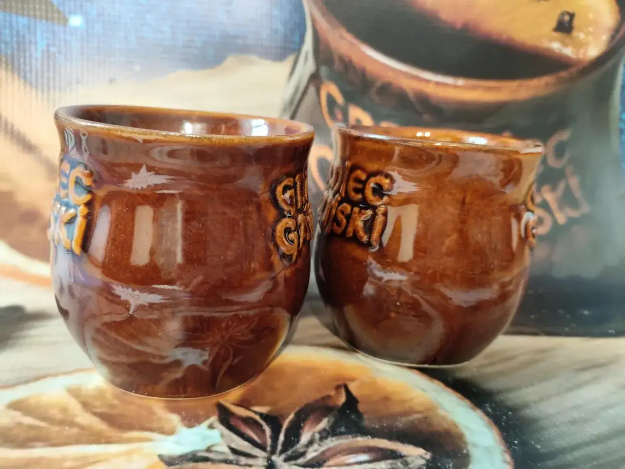 Dwa brązowe, ceramiczne kubeczki z napisem