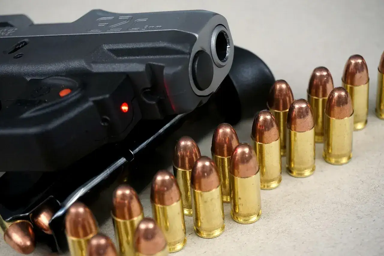 Ciemny pistolet z czerwonymi wskaźnikami i rzędem nabojów. Różne rodzaje pistoletów mogą wyglądać podobnie.