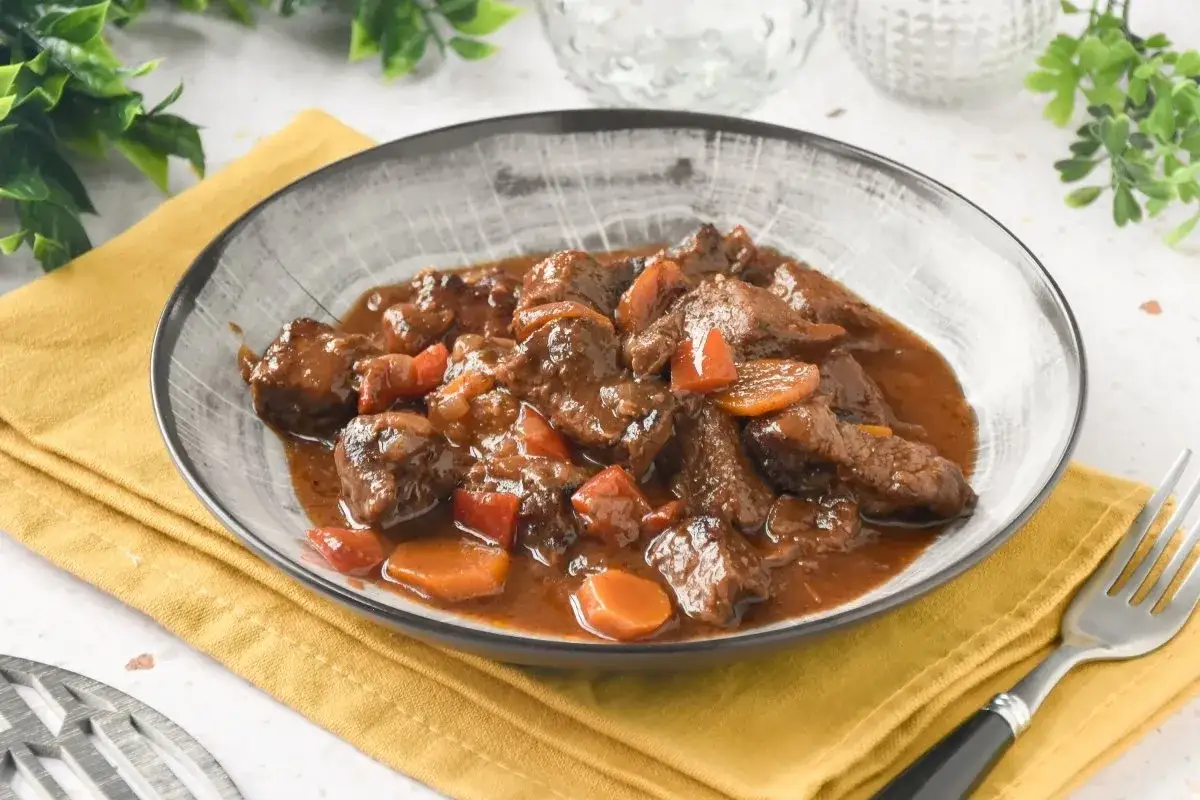 Un plato humeante de carne al toro, tiernos trozos de carne estofada con zanahorias y pimientos en una rica salsa.