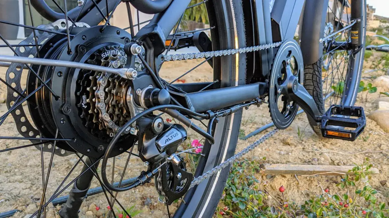 Widok tylnego koła roweru z widocznymi rodzajami przerzutek rowerowych: kasetą Shimano i przerzutką Altus.