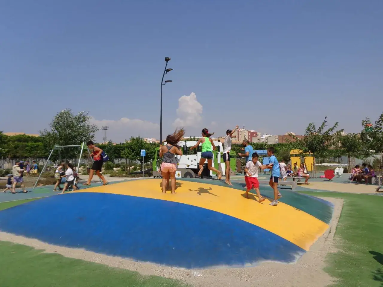 Niños saltando y jugando en un inflable gigante en el **parque de las familias**. Un día soleado y divertido para todos.