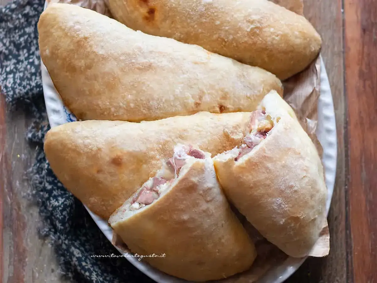 Panzerotti al forno dorati e ripieni di prosciutto e formaggio, pronti per essere gustati.