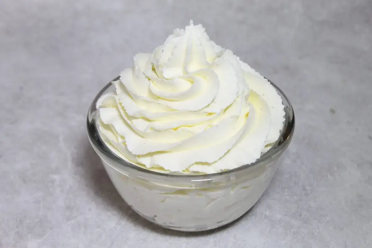 Chantilly aérienne, parfaitement montée au robot pâtissier, dans un bol en verre. Un délice crémeux prêt à garnir vos desserts.