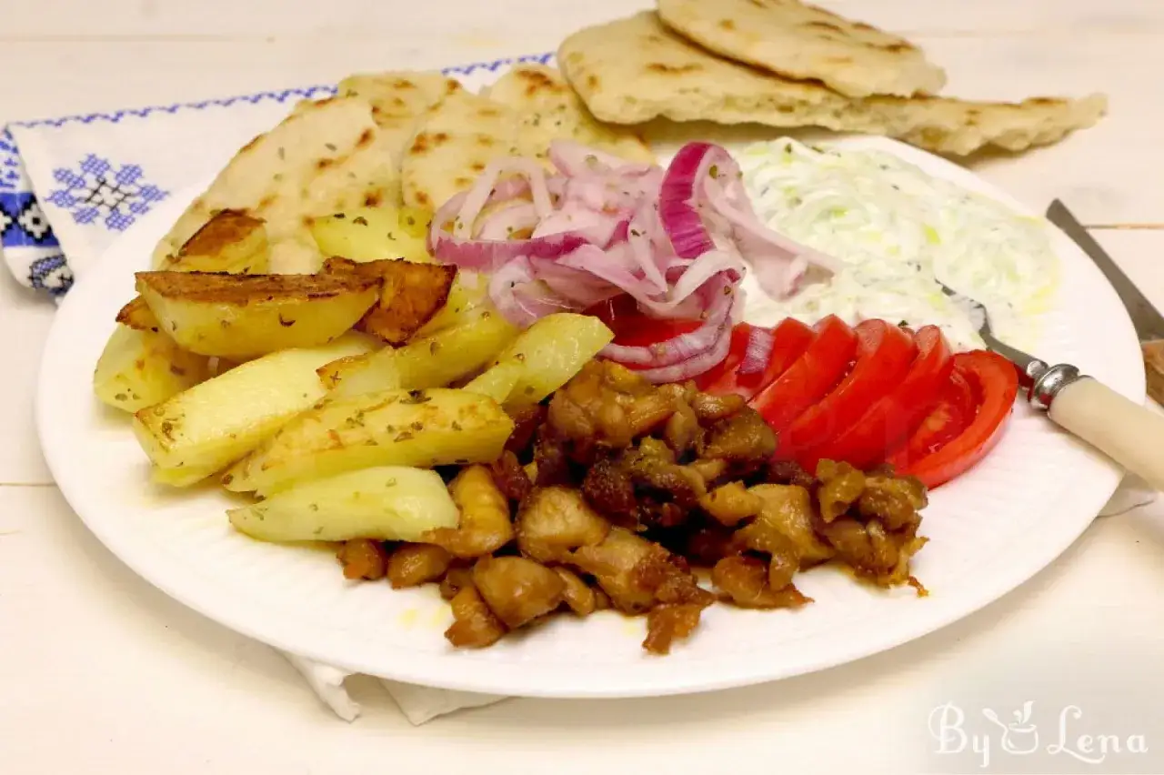 En tallrik med kyckling gyros, pommes frites, pitabr&ouml;d, tomater, r&ouml;dl&ouml;k och tzatziki.