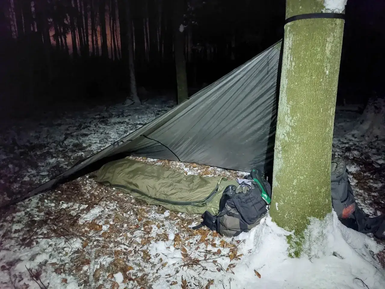 Nocne spanie pod namiotem w lesie, z karimatą i śpiworem gotowymi na zimno.
