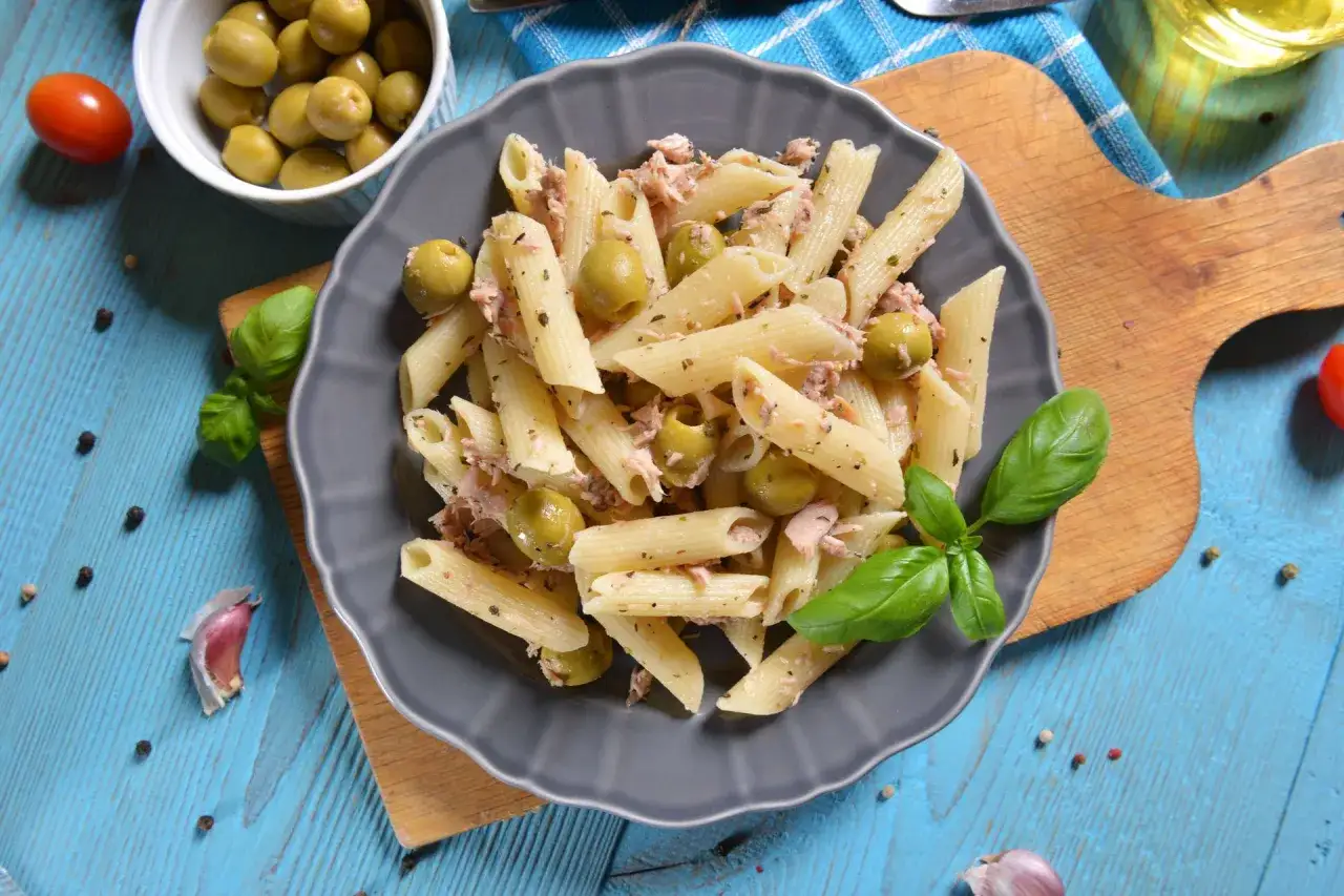 Penne z tuńczykiem i oliwkami, ozdobione bazylią. Proste i pyszne danie, idealne na szybki obiad.