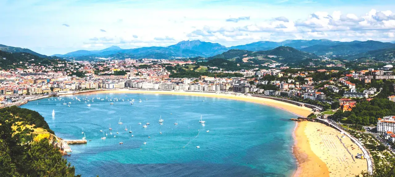 Widok na zatokę La Concha w San Sebastián, z plażą, licznymi łodziami i miastem w tle. To idealne miejsce na odkrywanie san sebastian atrakcje.