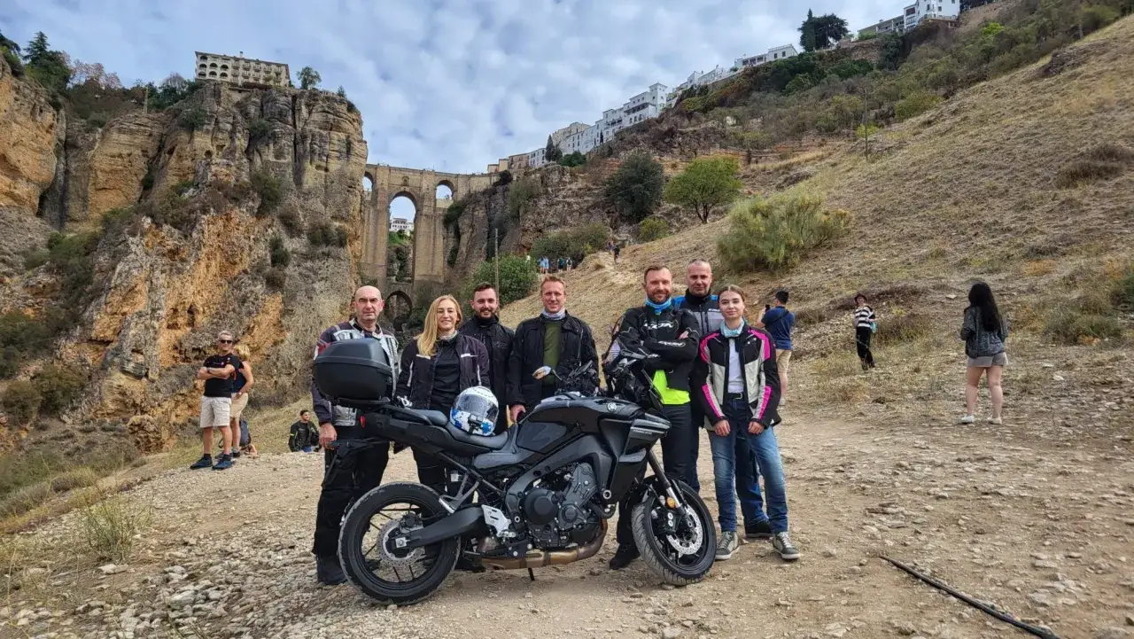 Grupa motocyklistów na tle Ronda w Andaluzji. To miejsce, które warto zobaczyć, z imponującym mostem i klifami.