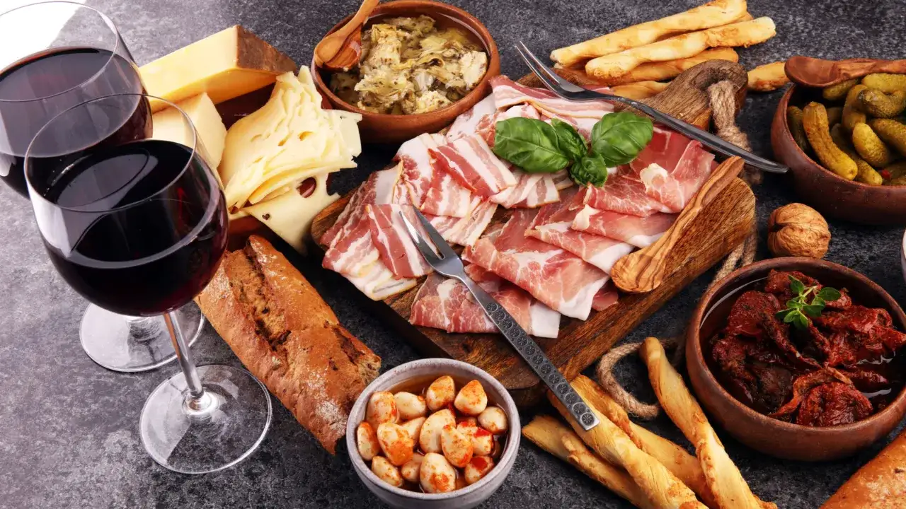 Zwei Gläser Rotwein, Käse, Brot, Schinken und Speck – ein Genuss für Liebhaber von **wein trocken**.