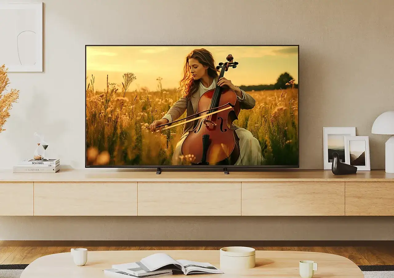 Kobieta gra na wiolonczeli na tle złotego pola, obraz wyświetlany na telewizorze Sony Bravia 5.