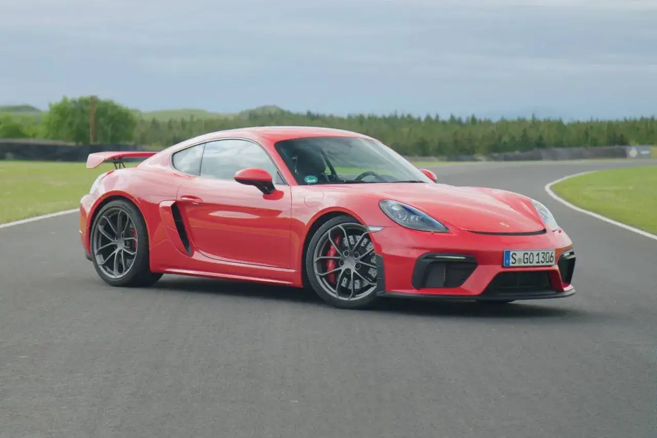 Roter Porsche GT4 auf Rennstrecke. Die technischen Daten dieses Sportwagens sind beeindruckend.
