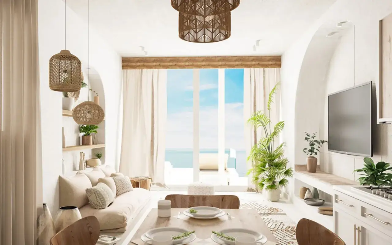 Un acogedor sal&oacute;n blanco y madera natural con vistas al mar. L&aacute;mparas de mimbre, sof&aacute; de lino y mesa de comedor.