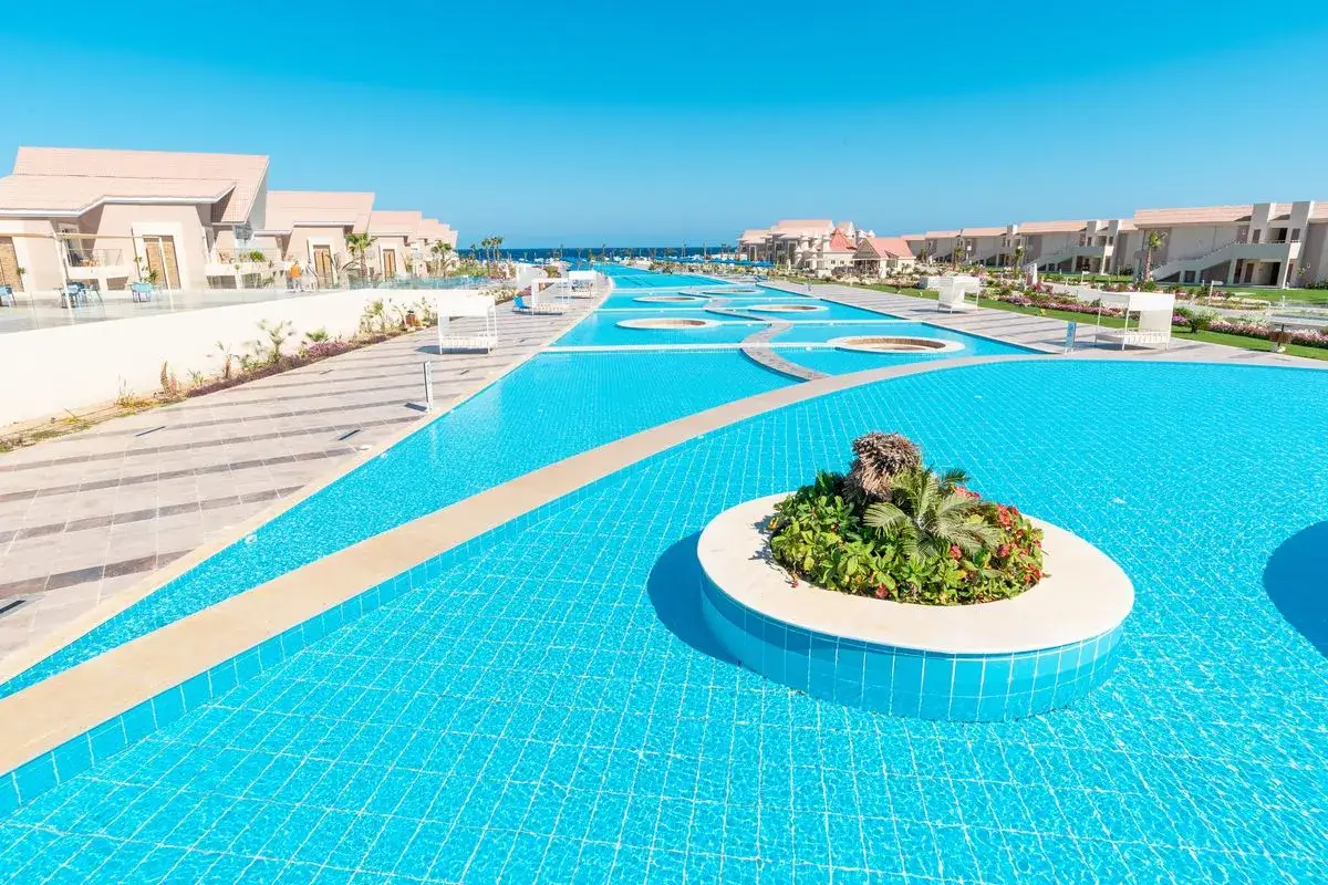 Luksusowy basen w Pickalbatros Sea World Marsa Alam, z palmami i leżakami, zaprasza do relaksu.