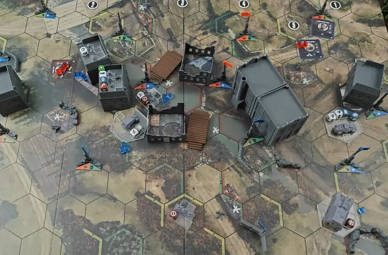 Plansza gry planszowej Company of Heroes z miniaturkami budynków, pojazdów i znacznikami.