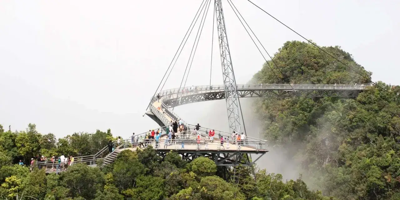 Einige Malaysia Highlights: Menschen genießen die Aussicht von der geschwungenen Skybridge, die sich durch üppige grüne Hügel schlängelt.