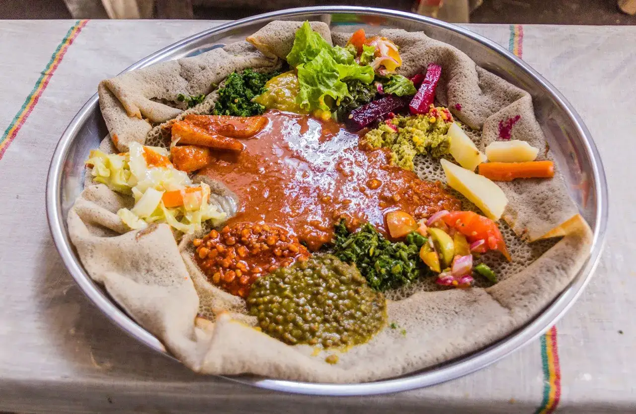Talerz pełen kolorowych potraw, serwowanych na placku injera. To tradycyjna kuchnia etiopska, gdzie każdy kęs to odkrycie smaków.