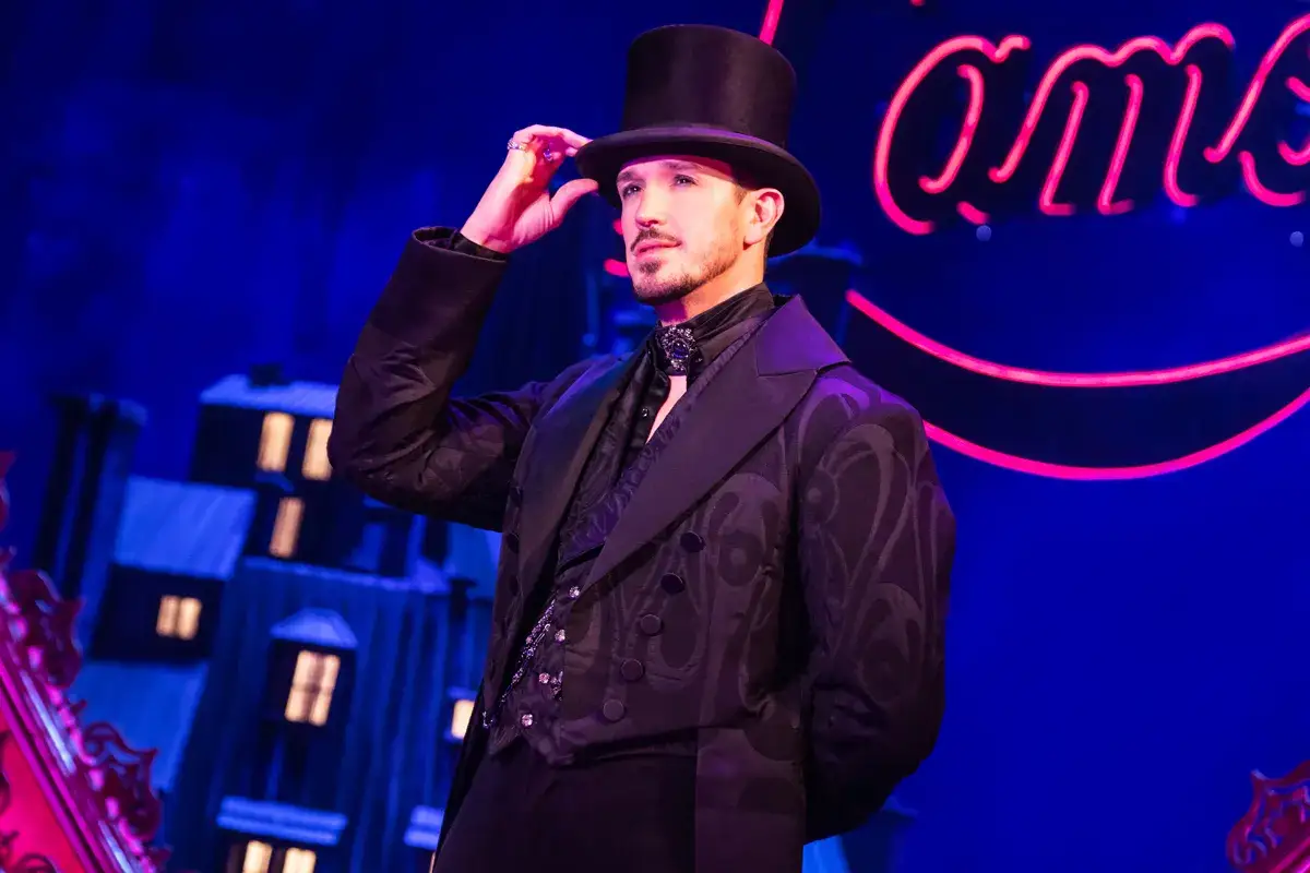 Aktor w cylindrze i ozdobnej marynarce kłania się na scenie, nawiązując do klimatu Moulin Rouge!