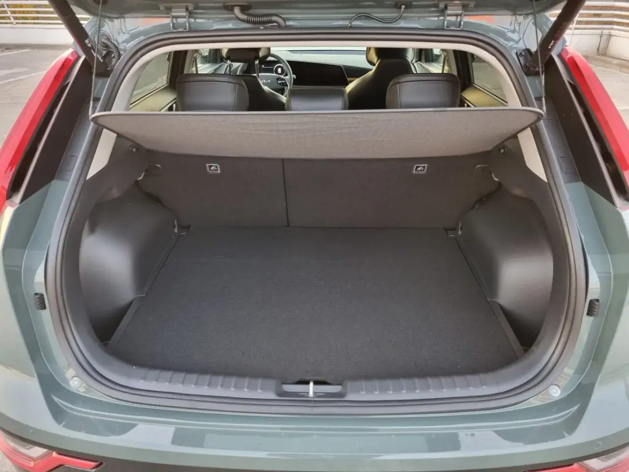 Pusty bagażnik Kia Niro Hybrid, gotowy na podróż. Wnętrze czyste, z widocznymi tylnymi siedzeniami.