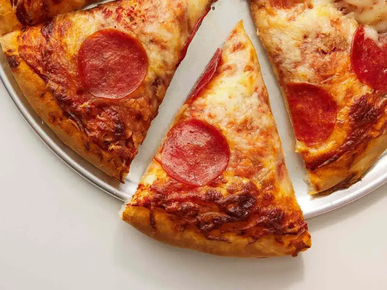 Kawałki pysznej pizzy pepperoni z ciągnącym się serem i chrupiącym ciastem.