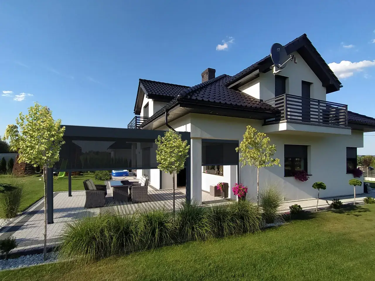 Nowoczesna pergola zacienia taras z meblami ogrodowymi, tworząc idealne miejsce do wypoczynku.