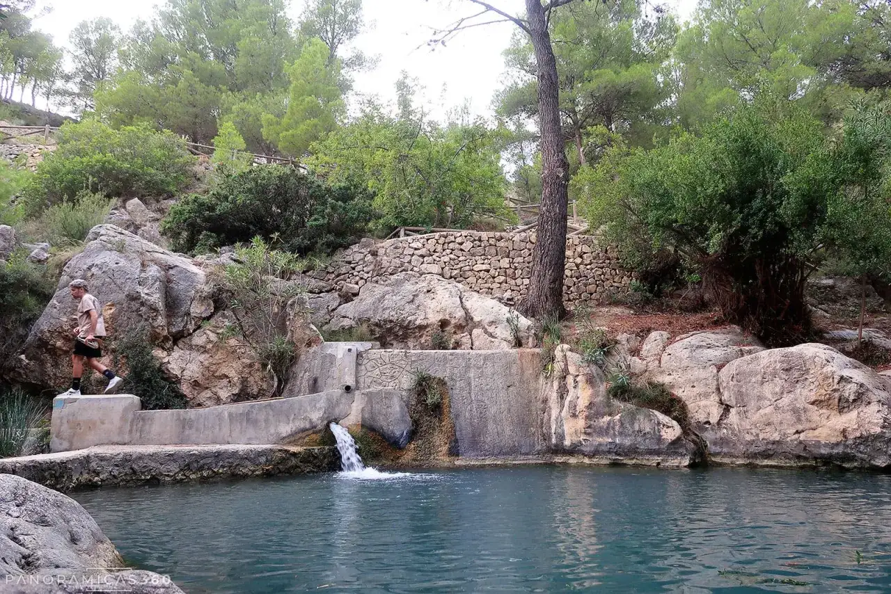 Un hombre camina junto a una cascada en un entorno natural, un lugar que parece un peque&ntilde;o para&iacute;so en Sella, Alicante.