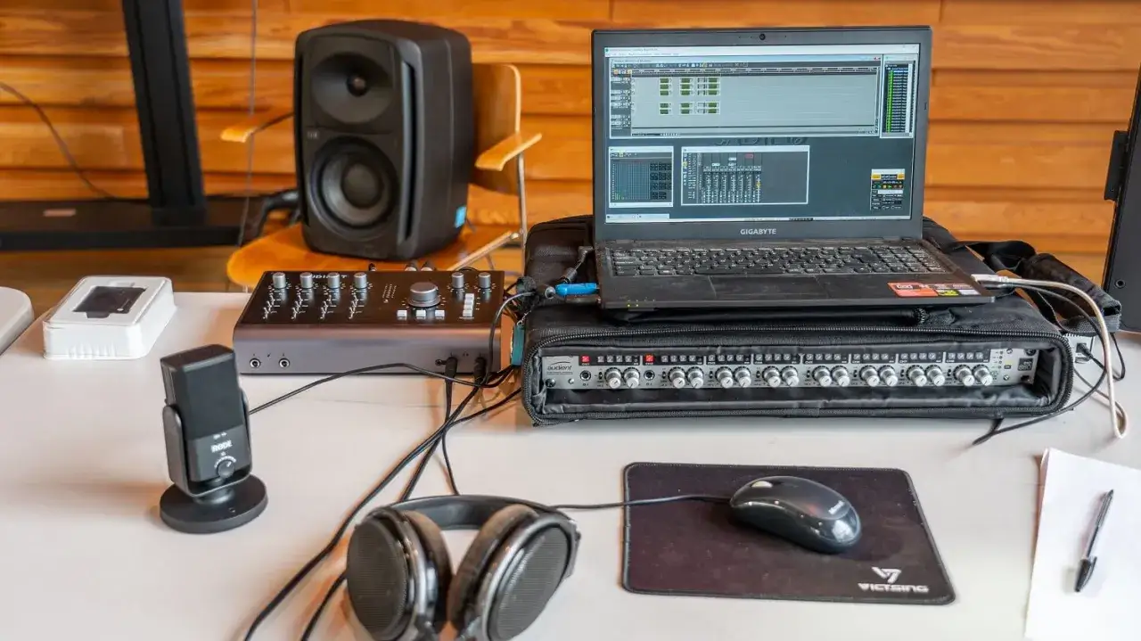Ein **Audient iD44** Audio-Interface mit Laptop, Monitorlautsprecher, Mikrofon und Kopfhörern für Musikproduktion.