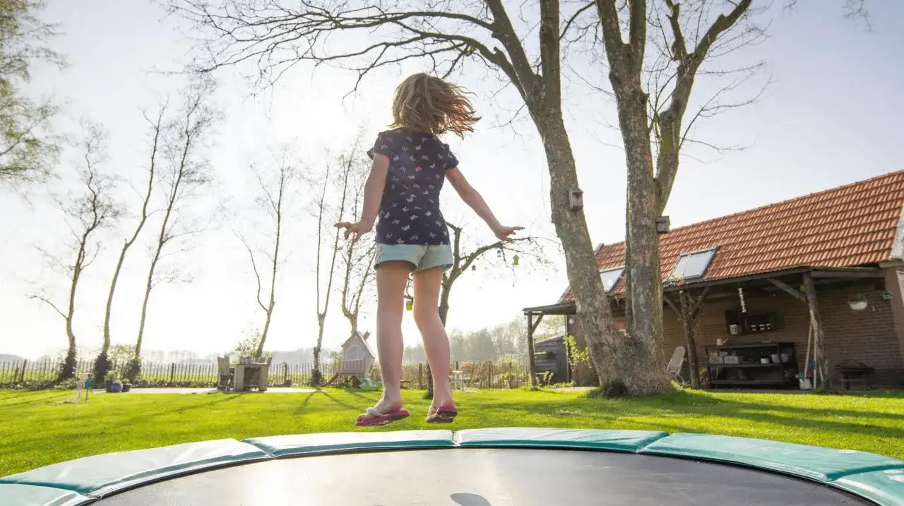Rodzic nadzorujący dziecko skaczące na trampolinie
