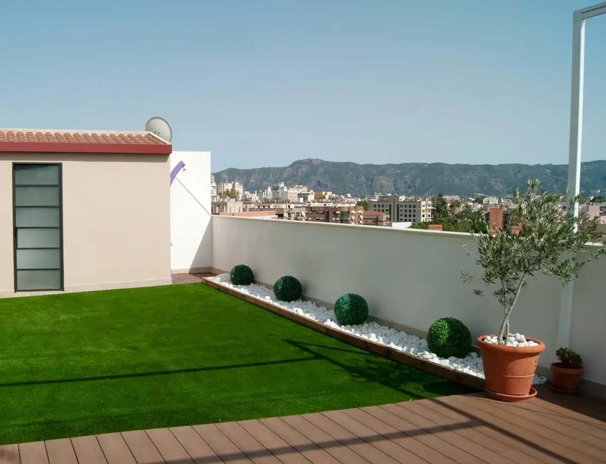 Terrazas con c&eacute;sped artificial: ideas para un oasis verde. Un balc&oacute;n moderno con c&eacute;sped artificial, plantas y vistas a la ciudad.