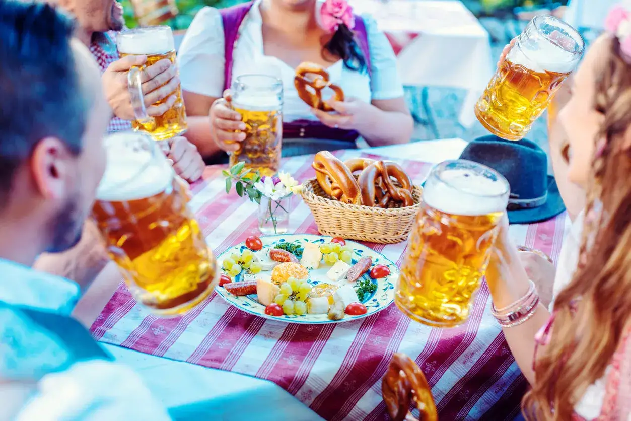 Biergarten-Stimmung mit Bierkrügen, Brezeln im Korb und einer Käseplatte.