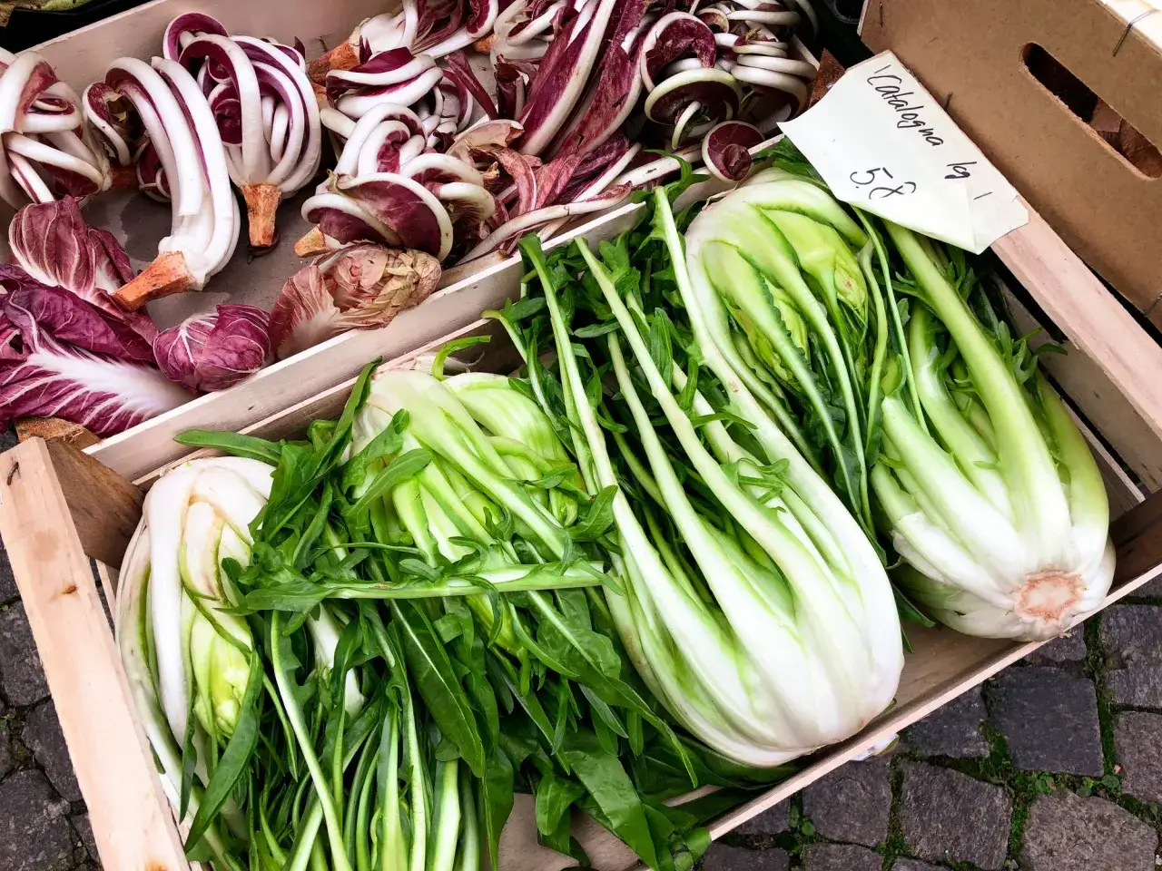 Verdure fresche in cassette di legno: radicchio rosso e catalogna, pronte per essere gustate.