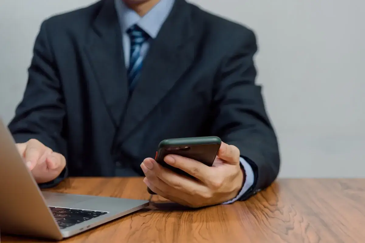 Un homme en costume utilise son t&eacute;l&eacute;phone, peut-&ecirc;tre victime d'usurpation d'identit&eacute; par t&eacute;l&eacute;phone.