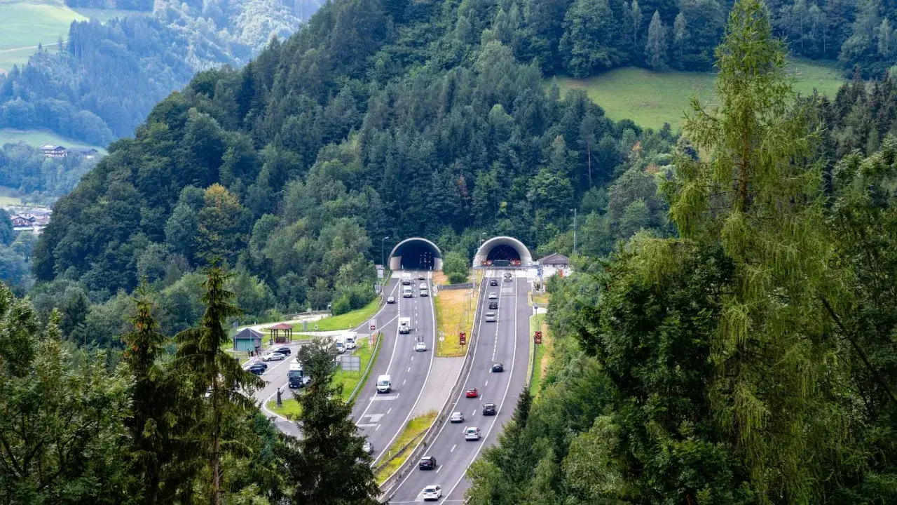 Dwie potężne **tunele Austria** wcinają się w zielone wzgórza, przez które pędzą samochody.